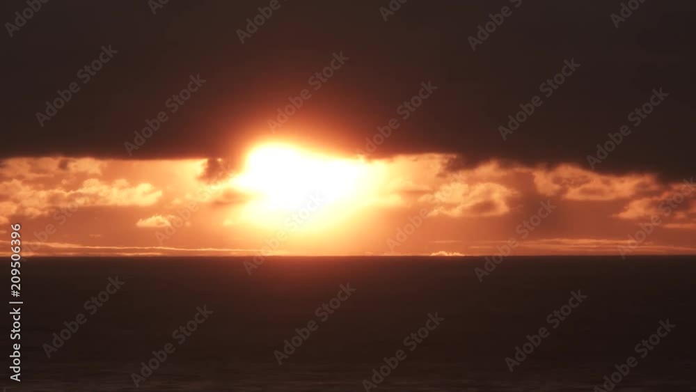 Bright and glowing sun drops below clouds and ocean horizon time lapse. Bright and glowing sun drops below clouds and ocean horizon time lapse.