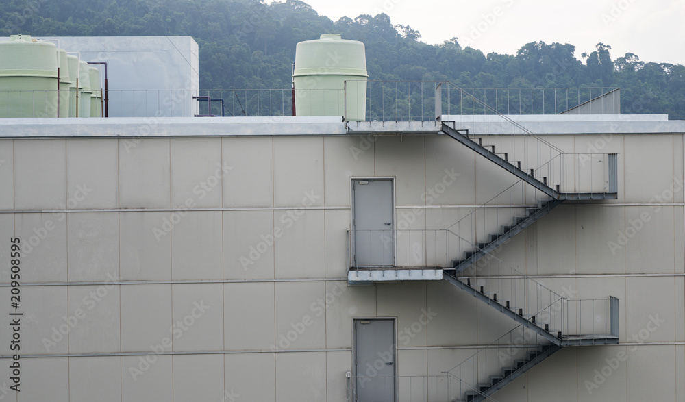 Naklejka premium Stair fire escape and Pipeline water at industrial building wall.