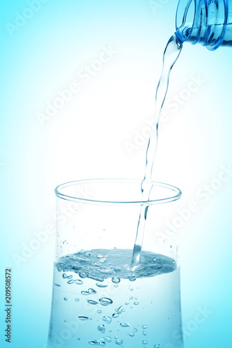 Pouring water from bottle into glass on white background.