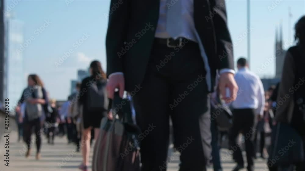 Defocused slow motion of commuters at rush hour on London Bridge, London.