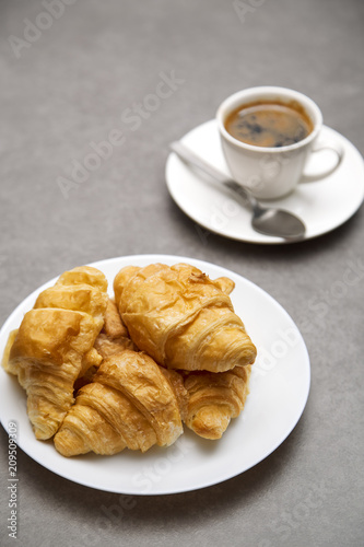 Cup of fresh coffee with croissants on dark background