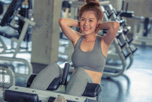 Young Asian happy fit woman lift torso train abdominal muscles workout at sport gym, bodybuilder do abs exercises concept.