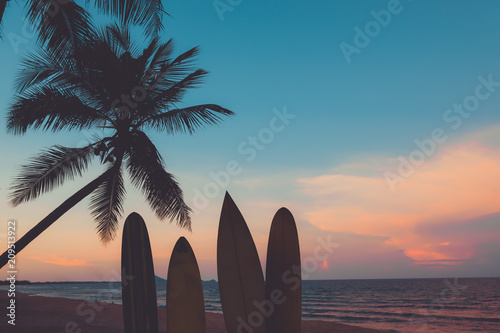 Silhouette surfboard on tropical beach at sunset in summer. Seascape of summer beach and palm tree at sunset. Vintage color tone