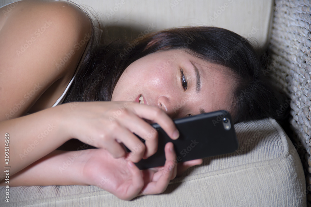 young sweet happy and pretty Asian Korean woman using internet social media app on mobile phone smiling cheerful lying on home sofa couch in online young sweet happy and pretty Asian Korean woman using internet social media app on mobile phone smiling cheerful lying on home sofa couch in online