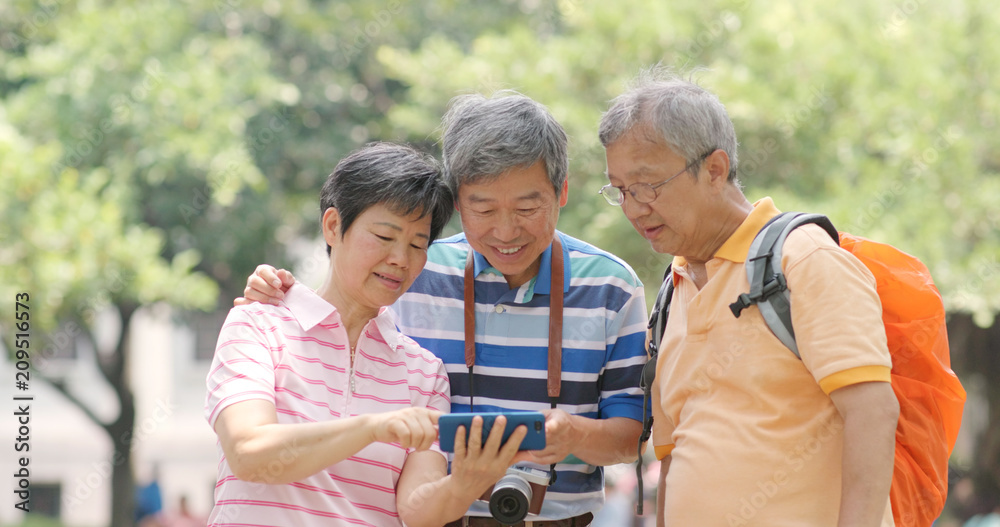 Senior old friends go travel together with backpack, cellphone and camera Senior old friends go travel together with backpack, cellphone and camera