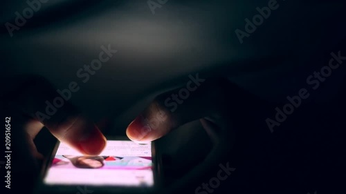 Close up of man hands typing scrolling pictures phone at night.