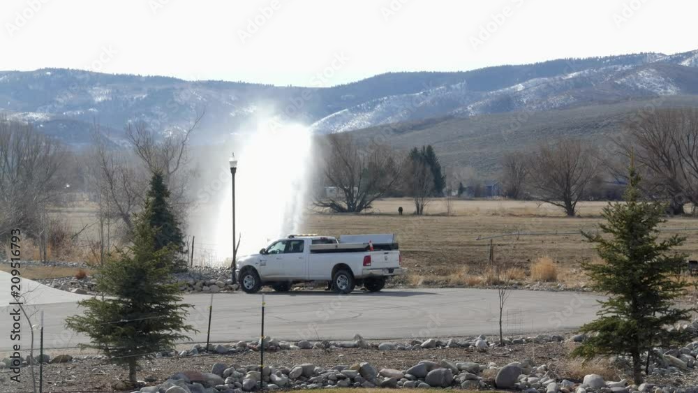 A geyser from a leaking fire hydrant at the end of a street A geyser from a leaking fire hydrant at the end of a street