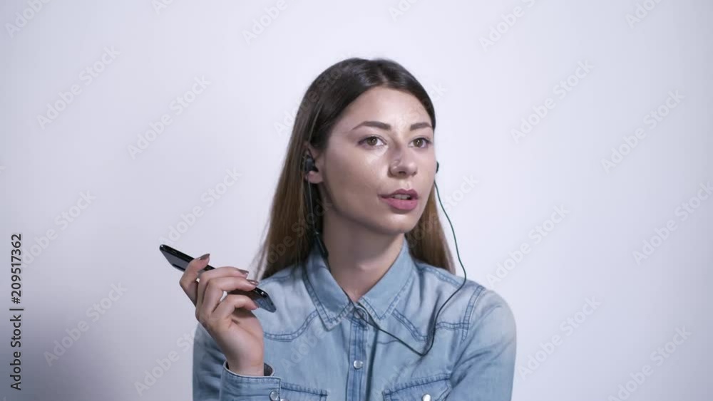 Ragazza con auricolari ascolta la musica e parla al telefono Ragazza con auricolari ascolta la musica e parla al telefono