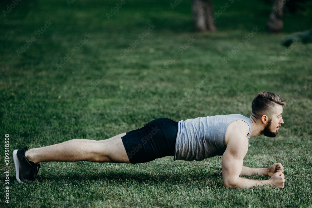 Muscular man at outdoor training doing plank exercise. Street fitness, sport, exercising, people and healthy lifestyle concept.