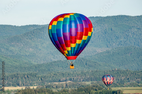 Hot air balloons flying over wooded hills