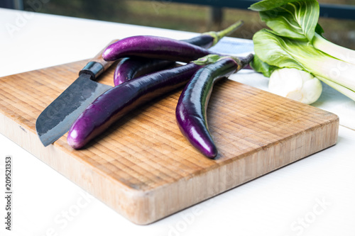 japanese eggplant on wooden board with knife and pak choi salad photo