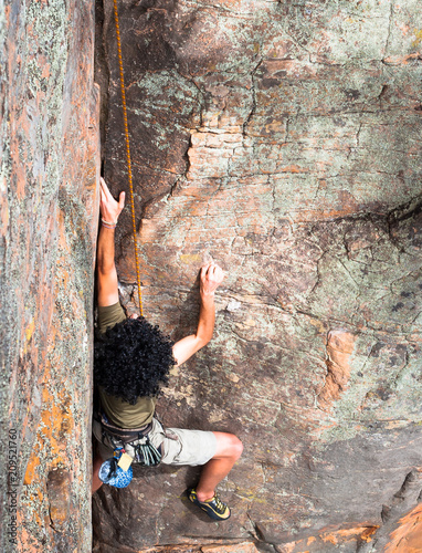 Fototapeta Naklejka Na Ścianę i Meble -  A climber with large black afro climbs a rock wall at the Black Ians climbing area in Victoria, Australia.