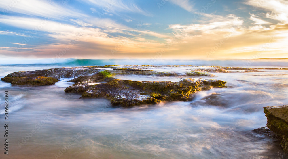 Long exposure of ocean waves flowing over rocky tidepools at sunset on Johanna Beach in the Great Otway National Park, Victoria, Australia. Long exposure of ocean waves flowing over rocky tidepools at sunset on Johanna Beach in the Great Otway National Park, Victoria, Australia.