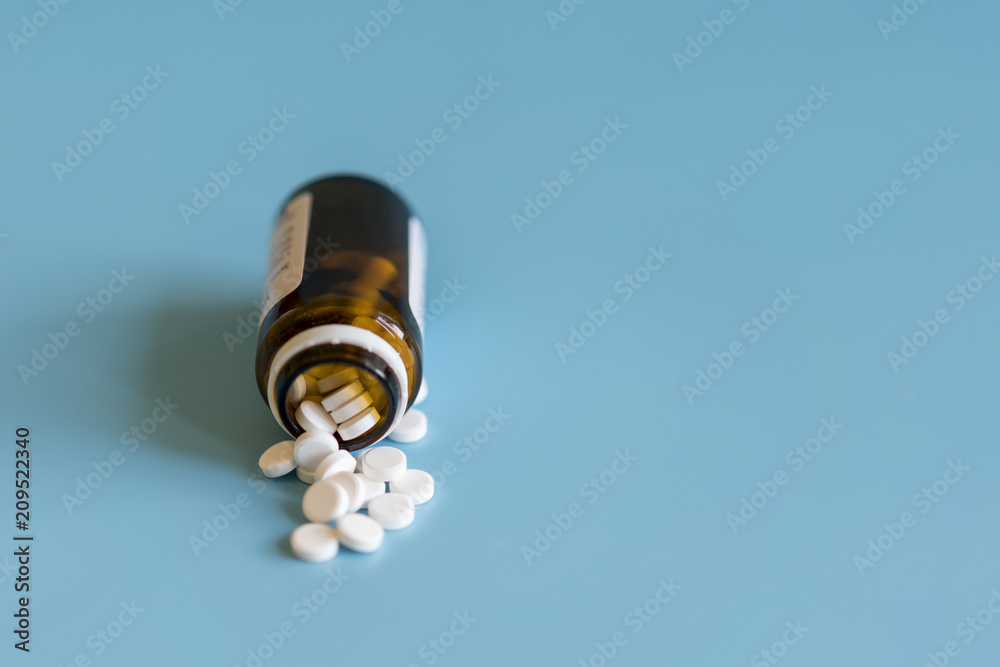 White tablets and bottle for tablets on blue background White tablets and bottle for tablets on blue background