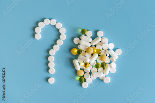 medicine pills, tablets and capsules symbol question mark on a blue background. White Tablets On Blue Background As Question Mark