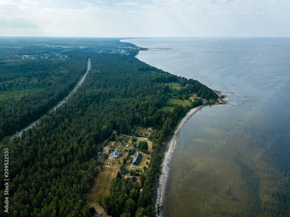 drone image. aerial view of Baltic sea shore with rocks and forest on land and highway near water