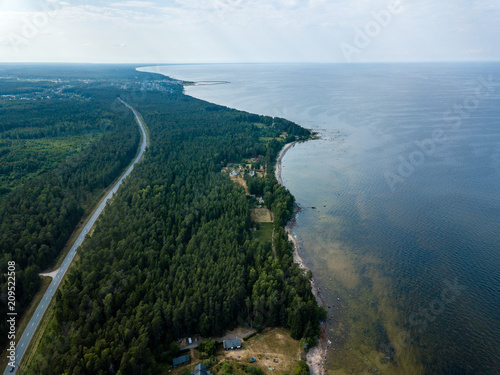 drone image. aerial view of Baltic sea shore with rocks and forest on land and highway near water