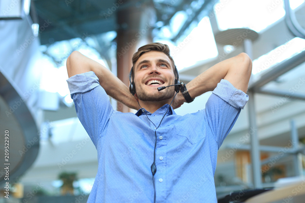 Call center operator in headset resting at workplace in office. Call center operator in headset resting at workplace in office.