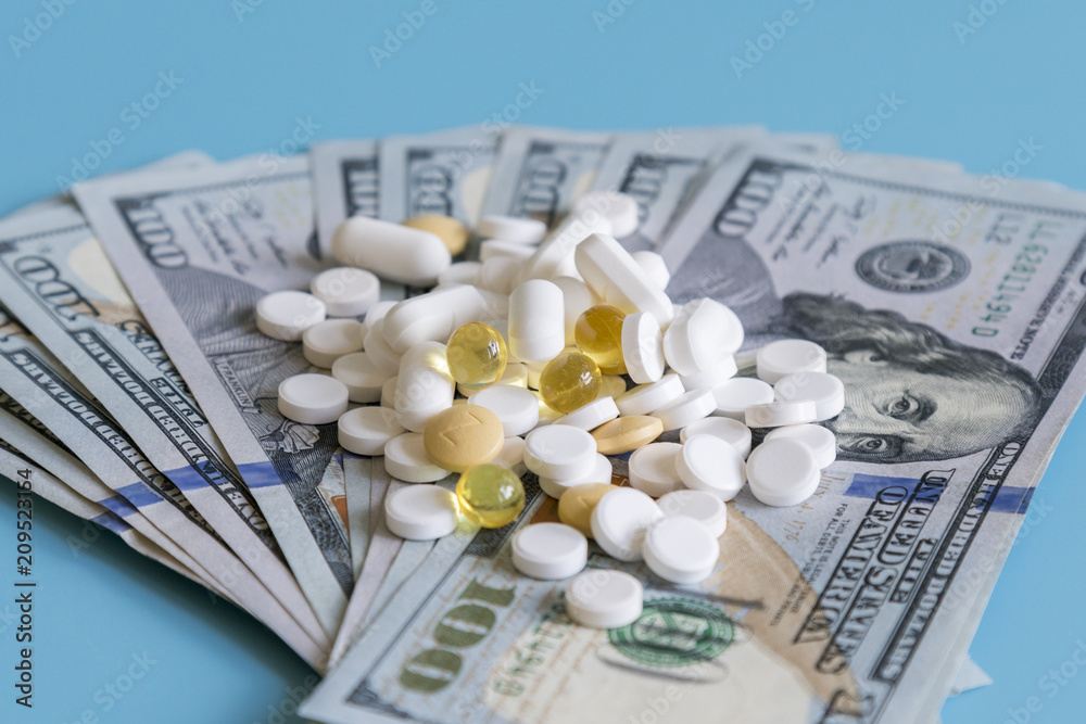 dollars pills medicine. Prescription medicine on dollars for pharmaceutical industry concept of high cost for healthcare and medication, top down view. dollars pills medicine. Prescription medicine on dollars for pharmaceutical industry concept of high cost for healthcare and medication, top down view.