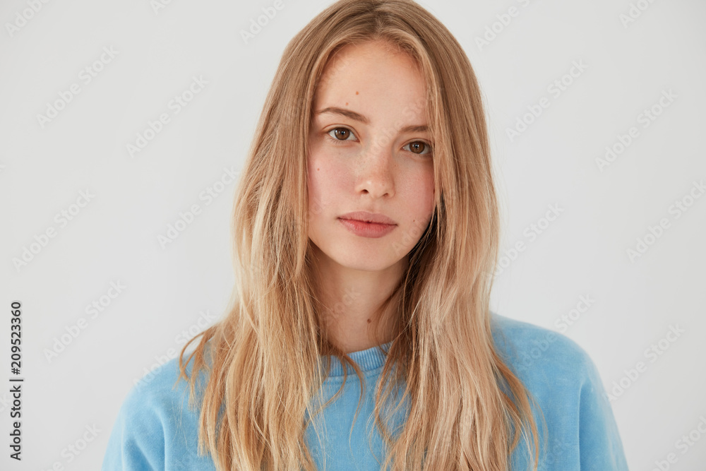 Adore me. Close up portrait of adorable young European female looks directly at camera, has appealing appearance, shows her beauty, has long staight hair, isolated over white studio background Adore me. Close up portrait of adorable young European female looks directly at camera, has appealing appearance, shows her beauty, has long staight hair, isolated over white studio background