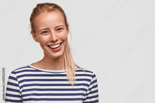 Portrait of postive glad adorable female student with pony tail, dressed in c...