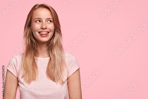 Horizontal shot of pretty happy female with broad smile, being in high spirit...