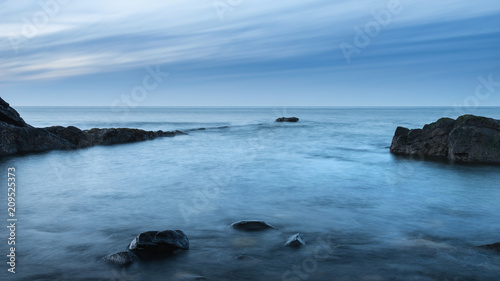 Beautiful long exposure landscape image of beach at Dunstanburgh in Northumberland England