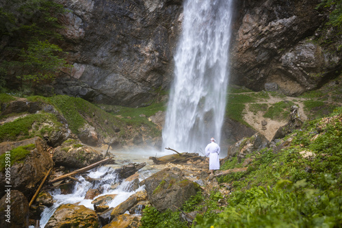 European man with beard is doing waterfall-meditation while standing under big waterfall in austria  wildensteiner waterfall