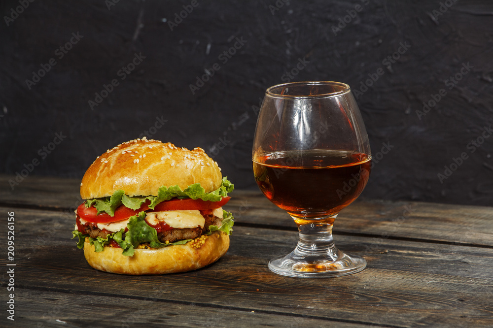 Hamburger on a wooden board against a dark background with copy space. Hamburger with sauce and fresh vegetables on a wooden table. Burger.