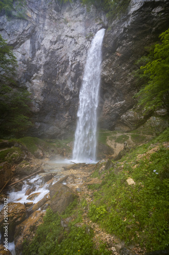 European man with beard is doing waterfall-meditation while standing under big waterfall in austria  wildensteiner waterfall