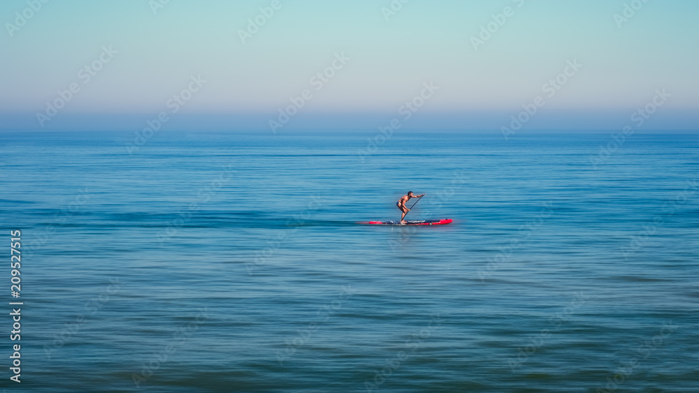 Stand up paddle board man paddleboarding standing on paddleboard on blue water