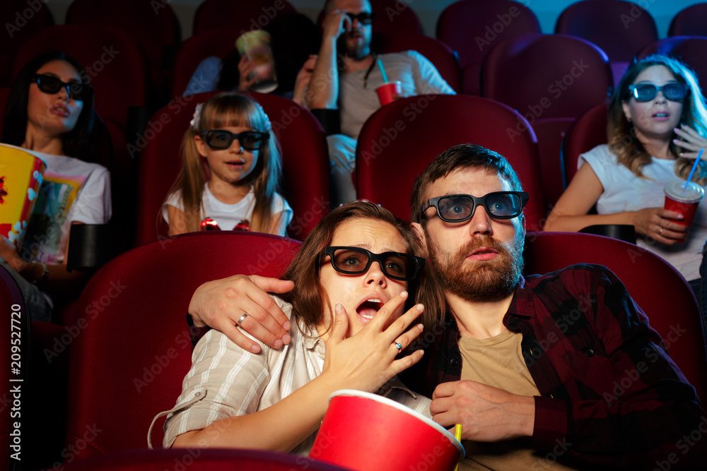 Obraz premium friends sitting in cinema watch film eating popcorn and drinking water.