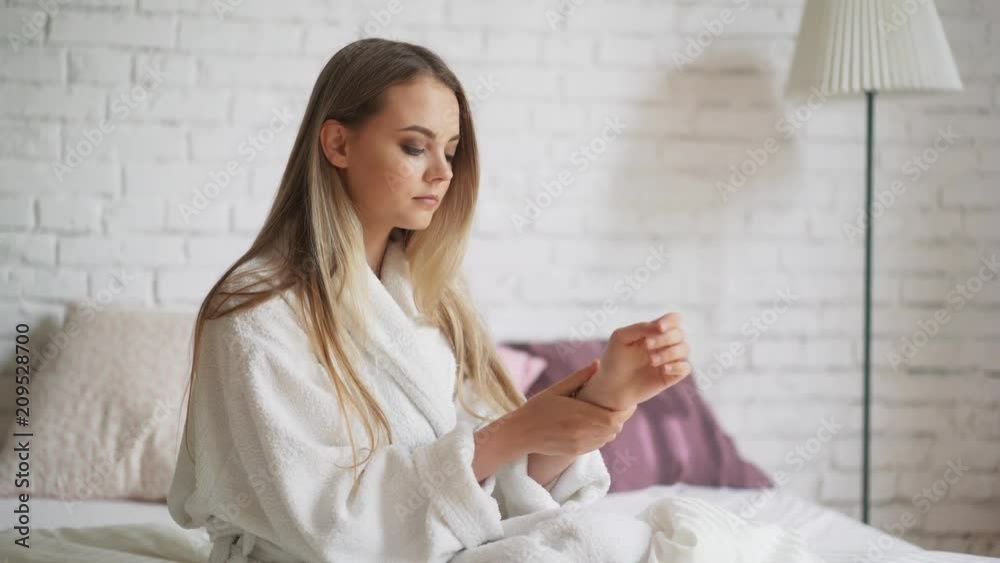 Cute girl in a bathrobe rubs his hands with cream Cute girl in a bathrobe rubs his hands with cream