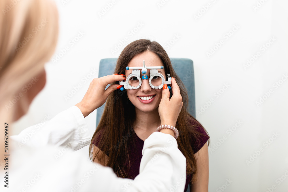 Female optometrist checking young and beautiful patient vision at eye clinic. Medical examination. Female optometrist checking young and beautiful patient vision at eye clinic. Medical examination.