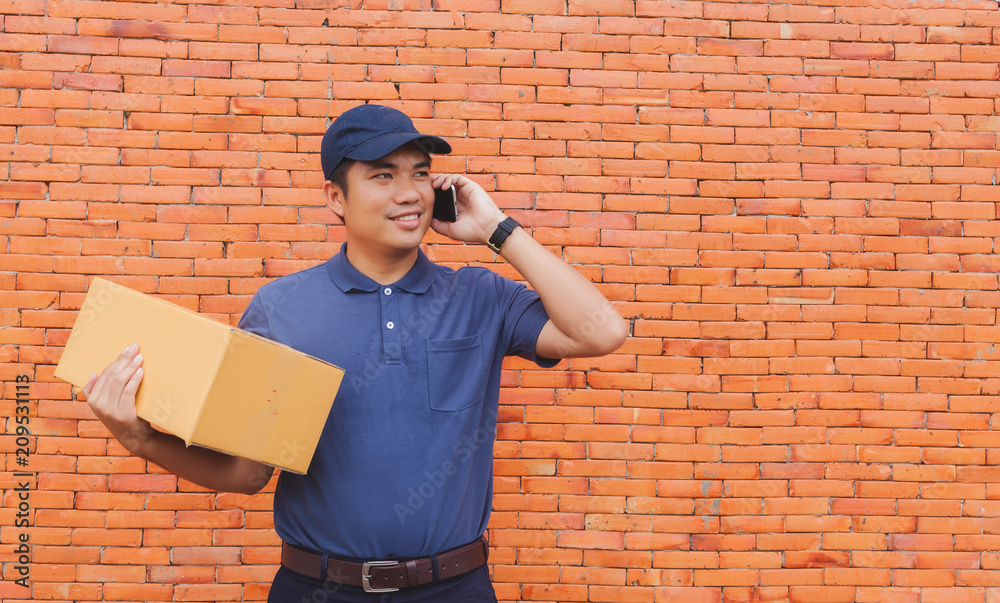 Asia delivery man are holding a cardboard box delivery to his customer.Delivery man are checking customer from the mobile. Asia delivery man are holding a cardboard box delivery to his customer.Delivery man are checking customer from the mobile.