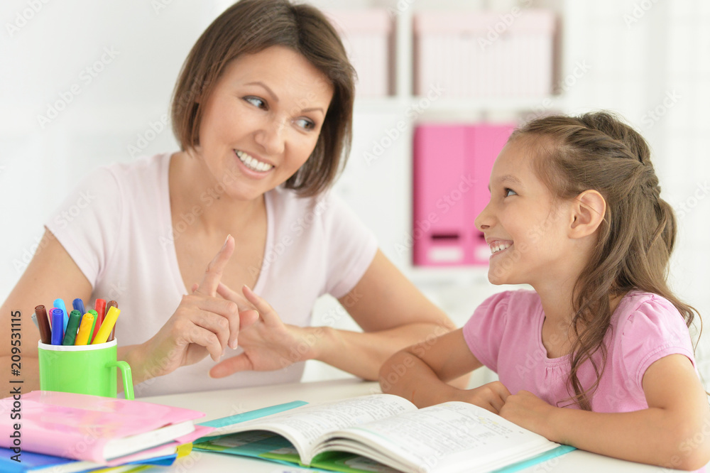 Pretty little girl and her mother doing homework Pretty little girl and her mother doing homework