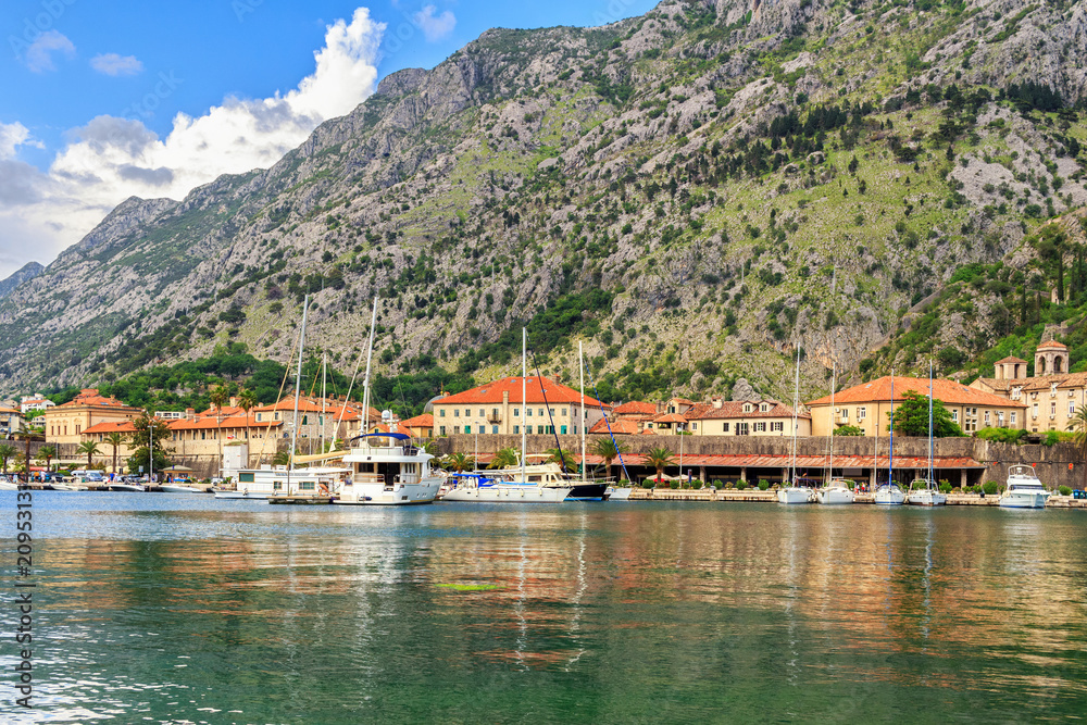 Adriatic sea coastline, view to the old city Kotor surrounded by mountains and marina with yachts and boats, Mediterranean summer landscape