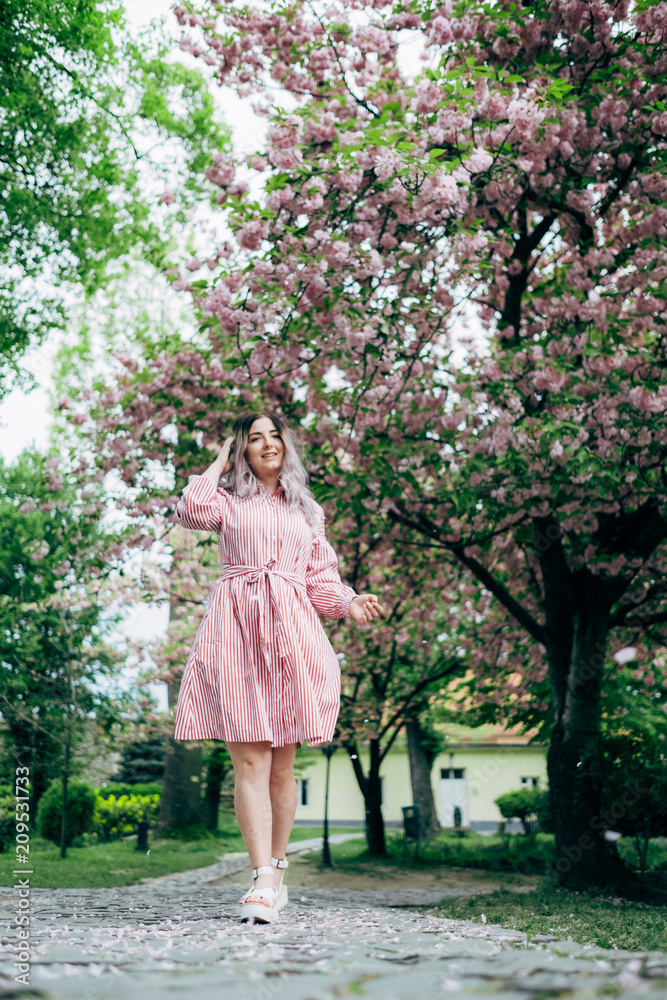 Young Woman in Red Striped Dress Walking in Garden Young Woman in Red Striped Dress Walking in Garden