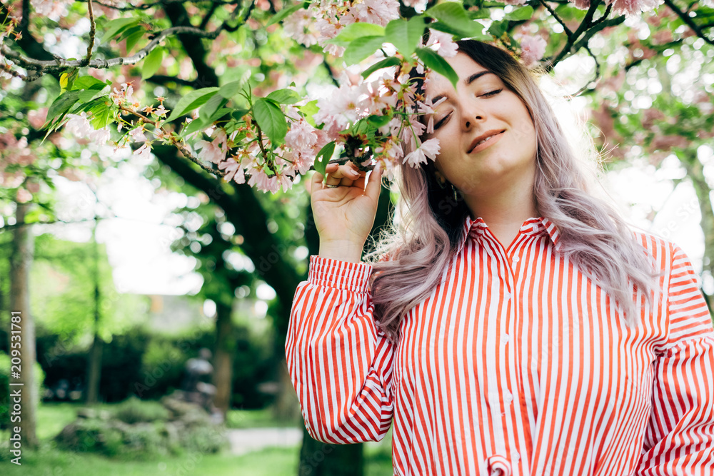 Beautiful Young Woman Enjoying Sunny Day in Park during Cherry Blossom Season Beautiful Young Woman Enjoying Sunny Day in Park during Cherry Blossom Season