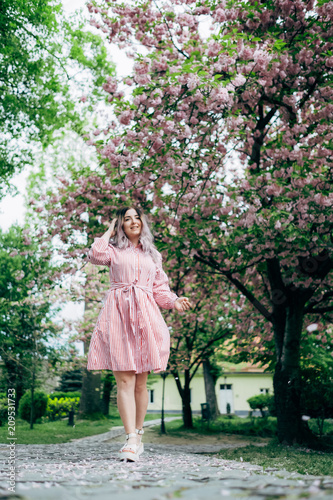 Young Woman in Red Striped Dress Walking in Garden