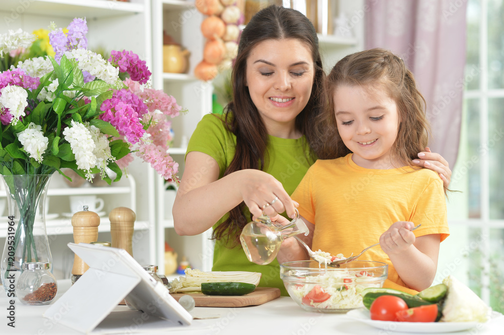 Cute little girl with her mother cooking together