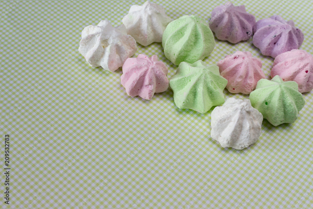 Several multicolor meringues on green background