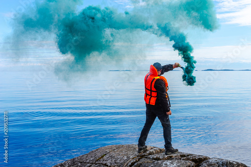 A man with a smoke torch. The rescue. Distress call. The man lights a smoke signal. A man in a life jacket. SOS photo