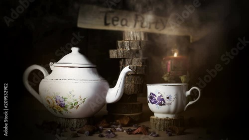 4K Cinemagraph - Cup of Tea and Teapot On Wooden Table With Arrow Sign, Smoke ,Candle Flame and Light in The Background. Tea Party Concept
