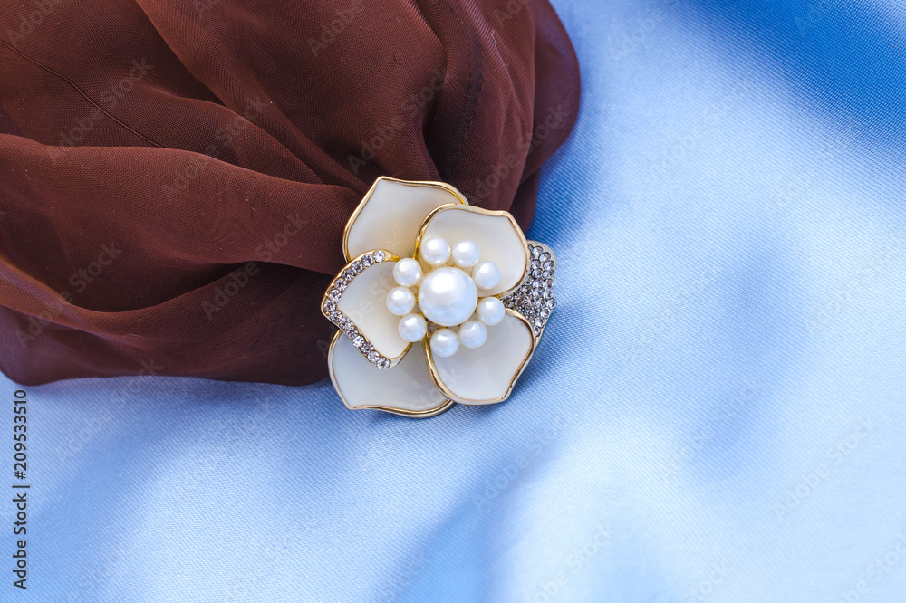 gold brooch flower with a pearls and diamonds isolated on silk gold brooch flower with a pearls and diamonds isolated on silk