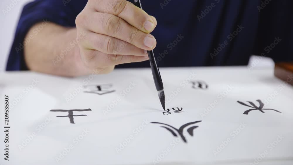 Art of drawing Chinese calligraphy characters close up 4K. Dolly slide shot of person hand in focus holding brush and concentrated drawing small characters in middle of bigger ones. Art of drawing Chinese calligraphy characters close up 4K. Dolly slide shot of person hand in focus holding brush and concentrated drawing small characters in middle of bigger ones.