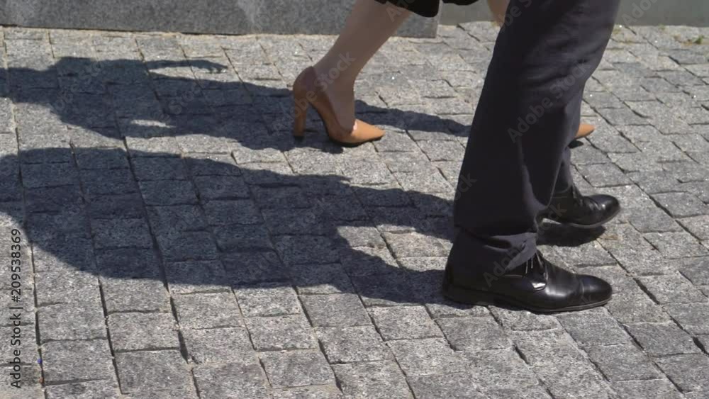 Business man and woman businesspeople going along the road near the office building and discussing the project. a woman in high-heeled shoes, a man in classic black shoes. 4K Business man and woman businesspeople going along the road near the office building and discussing the project. a woman in high-heeled shoes, a man in classic black shoes. 4K