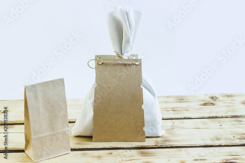A cloth bag with a place for an inscription and a paper bag on a wooden table
