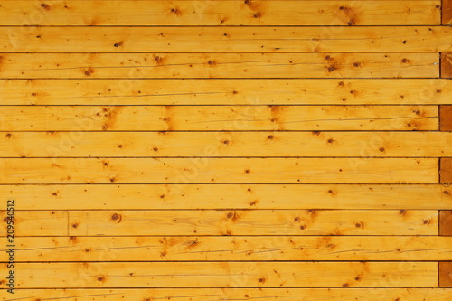 The wall of the house is made of a bar of new pine, treated with a protective layer. Close-up. Background. Texture.