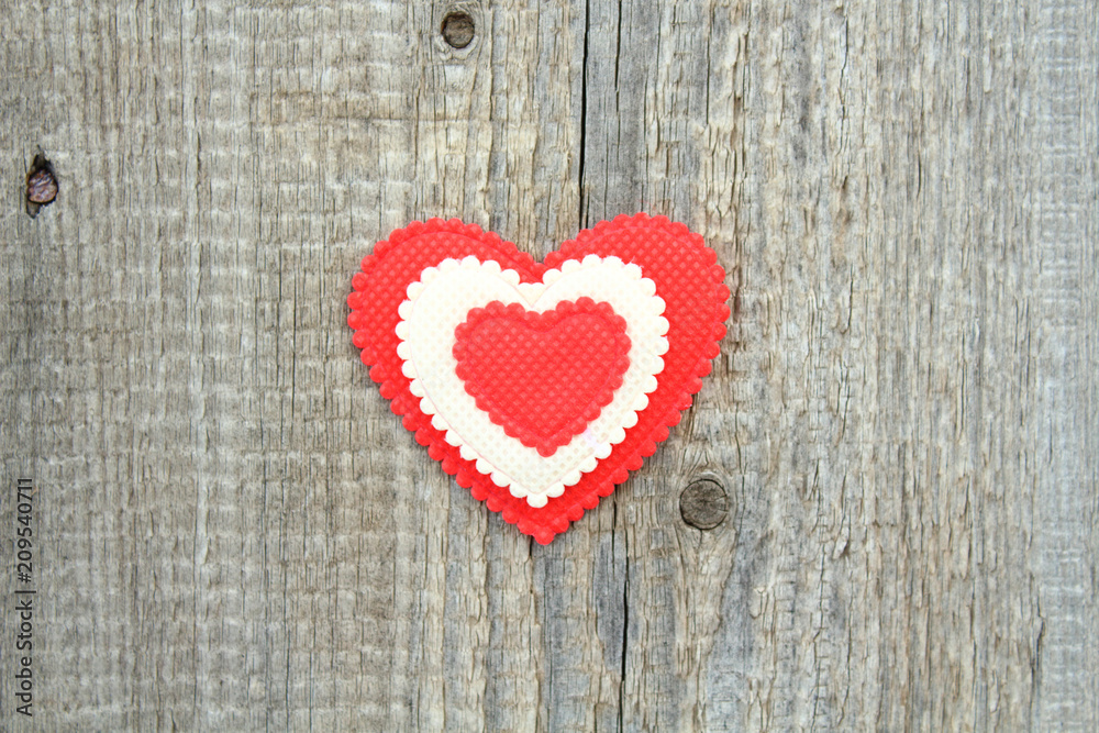 A beautiful soft heart made of cloth on an old board. Close-up. Background. Texture.